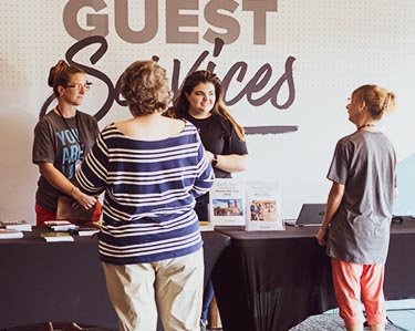 Churchgoers talking to volunteers at the Guest Services table