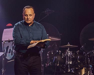 Pastor John preaching on stage